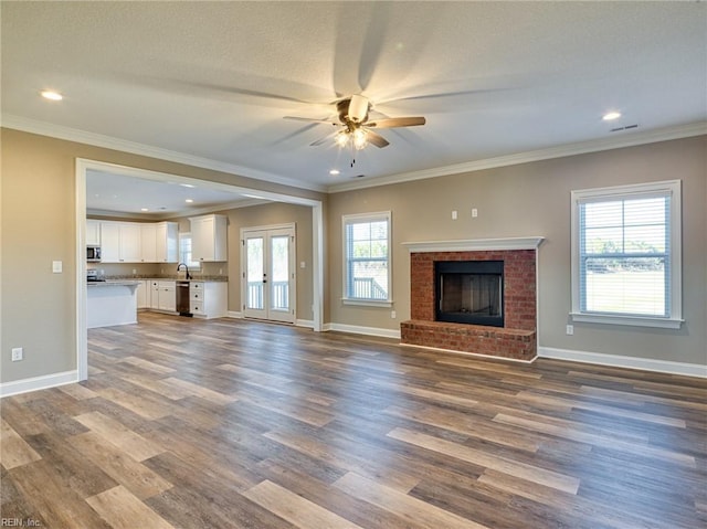 unfurnished living room featuring hardwood / wood-style flooring, crown molding, and french doors