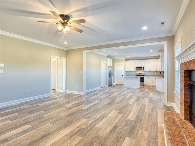 unfurnished living room with sink, crown molding, ceiling fan, light hardwood / wood-style floors, and a brick fireplace