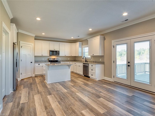 kitchen with stainless steel appliances, a kitchen island, sink, and white cabinets