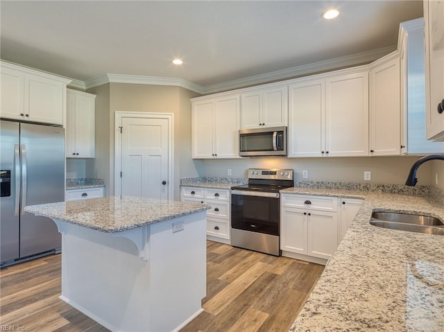 kitchen featuring white cabinetry, sink, a kitchen bar, stainless steel appliances, and light wood-type flooring