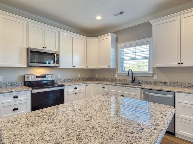 kitchen with sink, stainless steel appliances, ornamental molding, light stone countertops, and white cabinets