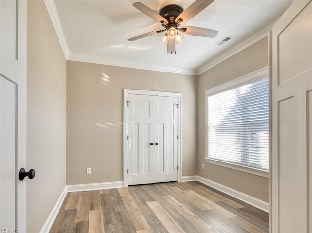 unfurnished bedroom with ceiling fan, ornamental molding, and light hardwood / wood-style flooring