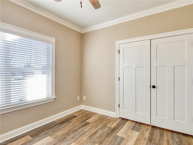 unfurnished bedroom with crown molding, ceiling fan, a closet, and light wood-type flooring