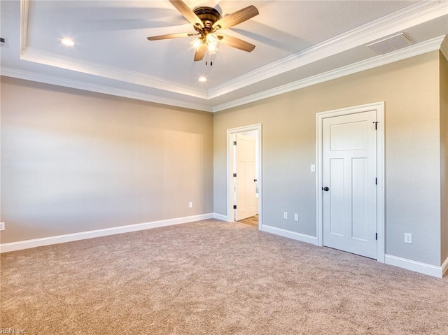 unfurnished bedroom with ceiling fan, ornamental molding, a tray ceiling, and light carpet