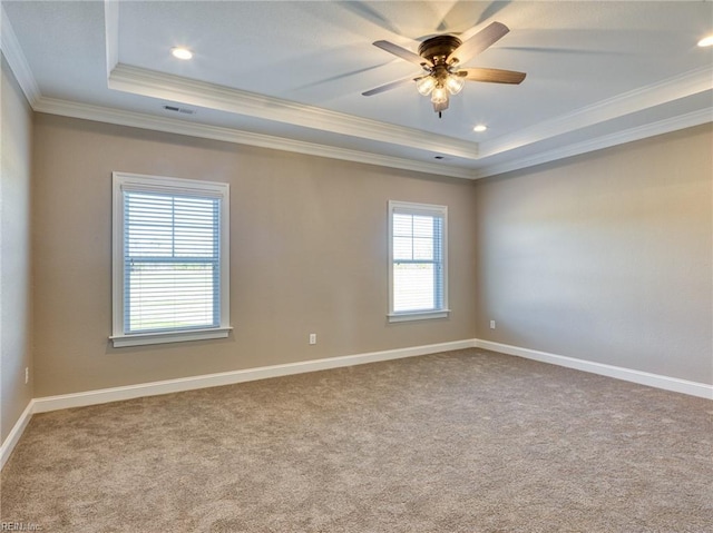 empty room featuring crown molding, a tray ceiling, light colored carpet, and ceiling fan