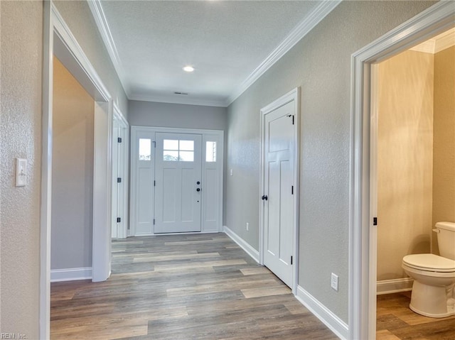 foyer with ornamental molding and light wood-type flooring