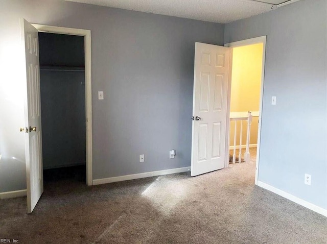 unfurnished bedroom featuring carpet flooring, a closet, and a spacious closet