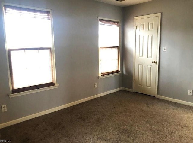 spare room with dark colored carpet