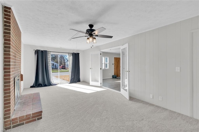 unfurnished living room with ceiling fan, light colored carpet, a textured ceiling, and french doors