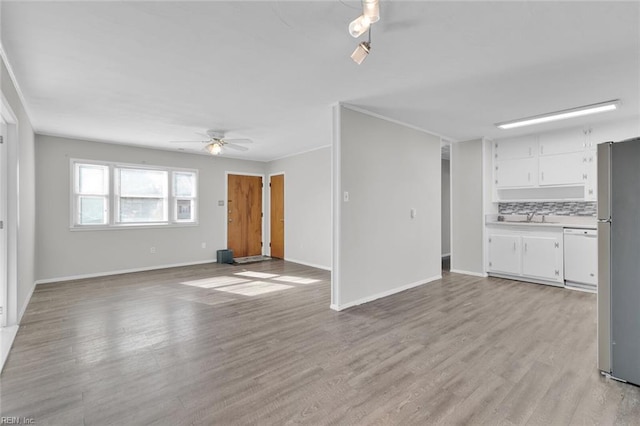 unfurnished living room with ceiling fan, sink, and light hardwood / wood-style floors