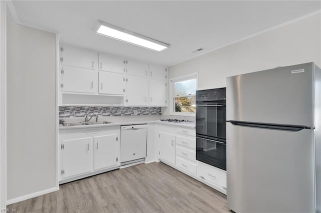 kitchen with sink, white appliances, tasteful backsplash, white cabinets, and light wood-type flooring