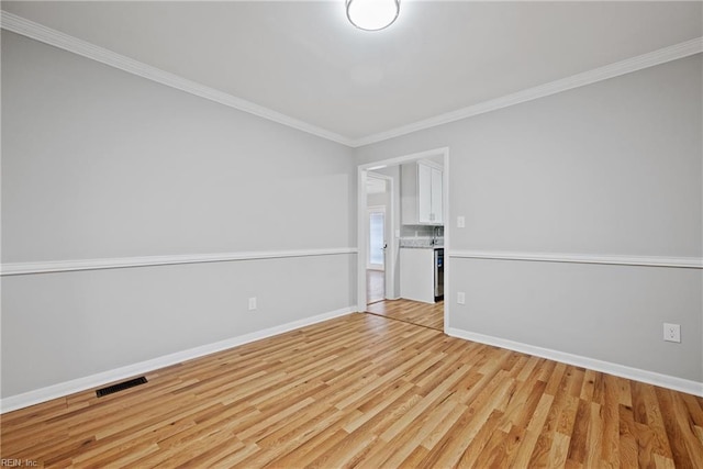 empty room with ornamental molding and light hardwood / wood-style flooring