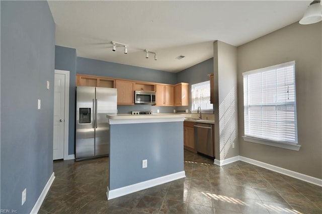 kitchen featuring track lighting, stainless steel appliances, a center island, and sink