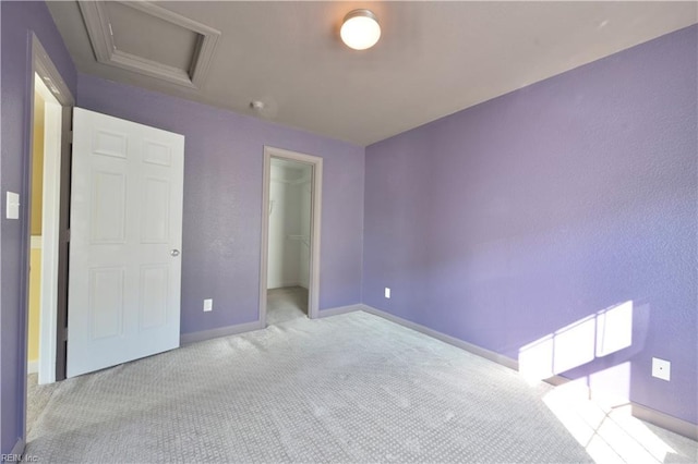 unfurnished bedroom featuring light carpet, a walk in closet, and a closet