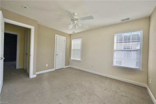 unfurnished bedroom featuring ceiling fan, multiple windows, a closet, and light carpet