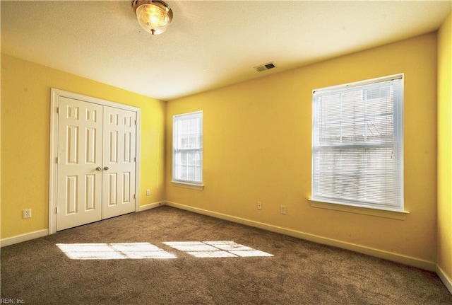 unfurnished bedroom featuring dark carpet and a closet