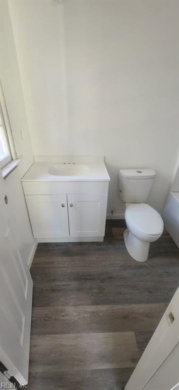 bathroom featuring hardwood / wood-style flooring, vanity, a washtub, and toilet