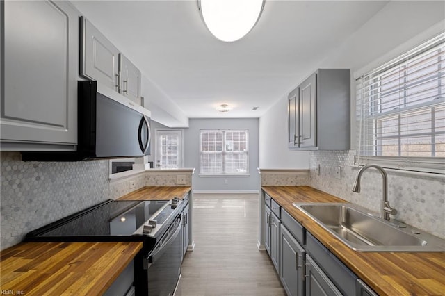 kitchen with wood counters, stainless steel appliances, sink, and gray cabinetry