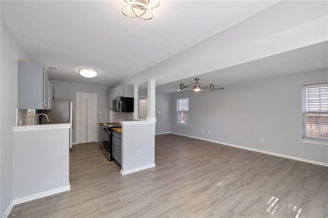 kitchen featuring gray cabinetry, hardwood / wood-style flooring, a wealth of natural light, and stainless steel appliances