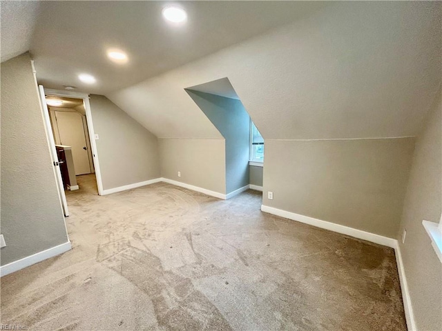 additional living space with vaulted ceiling and light carpet