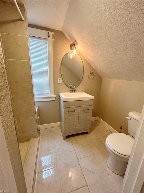 bathroom featuring vanity, toilet, vaulted ceiling, and a textured ceiling