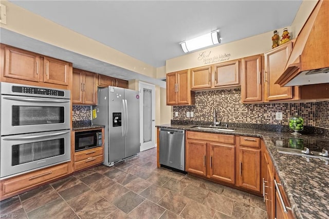 kitchen with appliances with stainless steel finishes, sink, backsplash, dark stone counters, and custom range hood