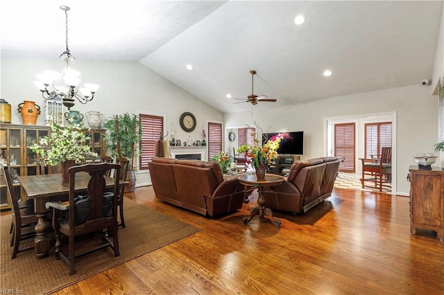 living room with hardwood / wood-style flooring, ceiling fan with notable chandelier, and vaulted ceiling