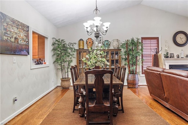 dining area featuring an inviting chandelier, lofted ceiling, and light hardwood / wood-style flooring