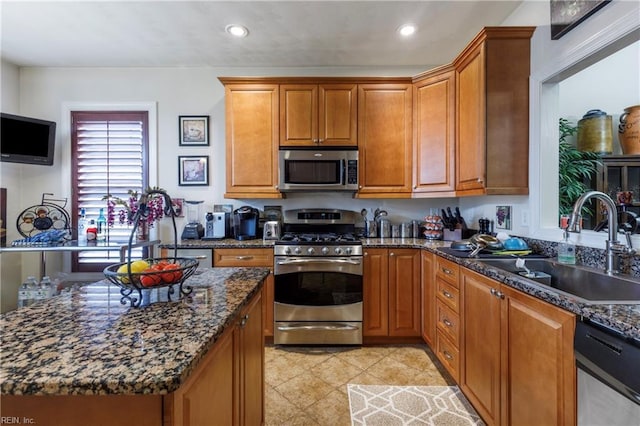 kitchen featuring dark stone countertops, sink, light tile patterned floors, and appliances with stainless steel finishes