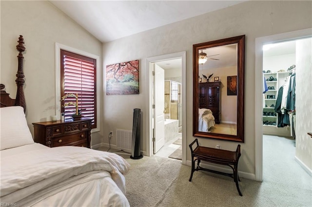 carpeted bedroom featuring vaulted ceiling, a walk in closet, ensuite bathroom, and a closet