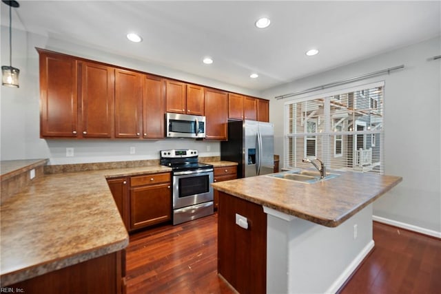 kitchen featuring sink, appliances with stainless steel finishes, a kitchen island with sink, hanging light fixtures, and dark hardwood / wood-style floors