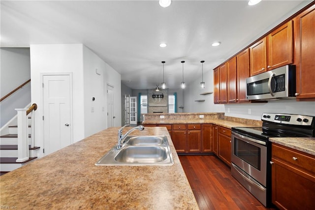 kitchen with pendant lighting, sink, kitchen peninsula, stainless steel appliances, and dark wood-type flooring