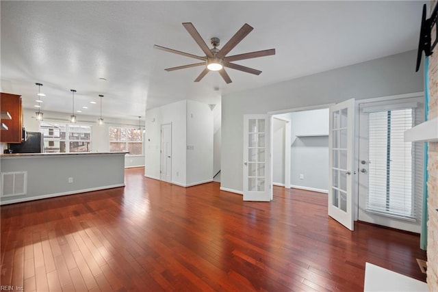 unfurnished living room with dark wood-style floors, french doors, visible vents, a ceiling fan, and baseboards