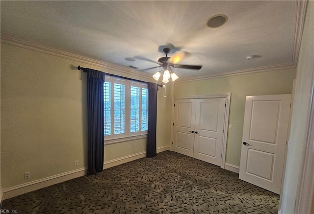 unfurnished bedroom featuring dark carpet, crown molding, a closet, and ceiling fan