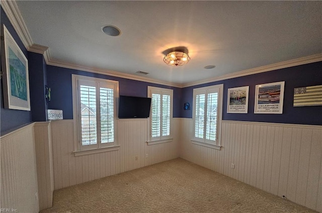 empty room with ornamental molding and light colored carpet