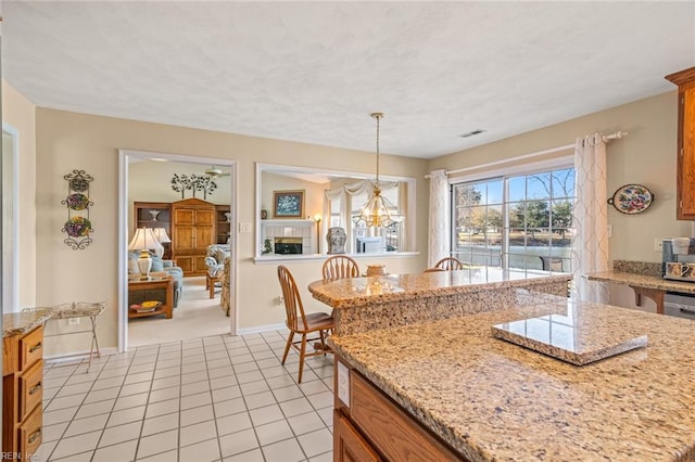 kitchen with light tile patterned flooring, decorative light fixtures, and light stone countertops