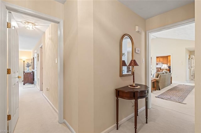 hallway featuring vaulted ceiling and light carpet