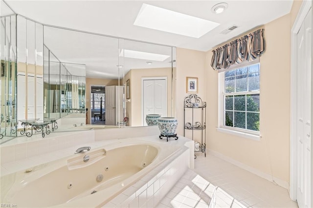 bathroom with a relaxing tiled tub, a skylight, and tile patterned flooring