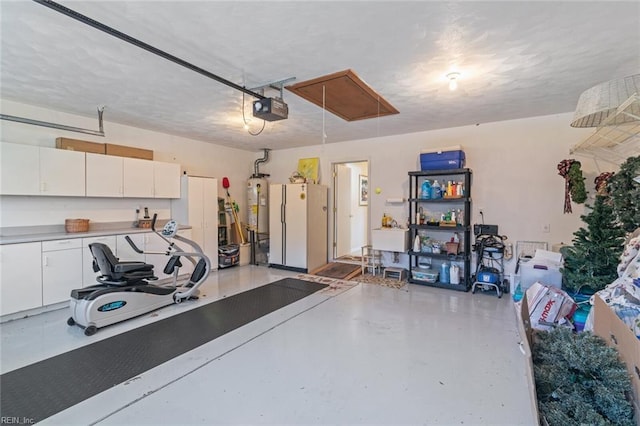 garage featuring a garage door opener, gas water heater, and white fridge