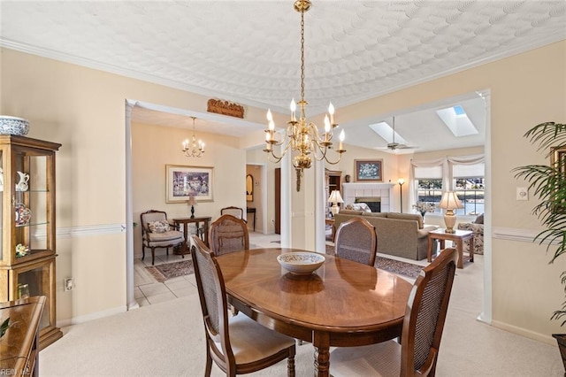 carpeted dining space with ornamental molding, a chandelier, a fireplace, and a skylight