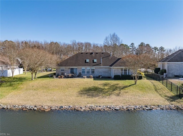 back of property with a lawn and a water view