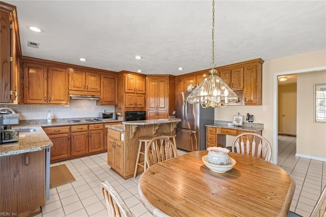 kitchen with light stone counters, light tile patterned floors, black appliances, and a center island