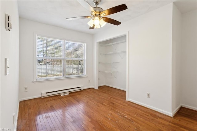 unfurnished bedroom with ceiling fan, a baseboard radiator, a closet, and wood-type flooring