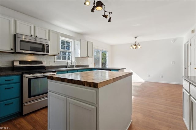 kitchen featuring pendant lighting, wooden counters, backsplash, stainless steel appliances, and a center island