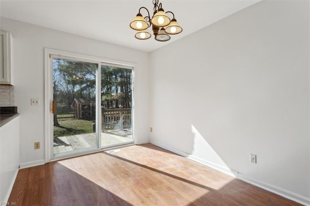 unfurnished dining area with wood-type flooring and a chandelier