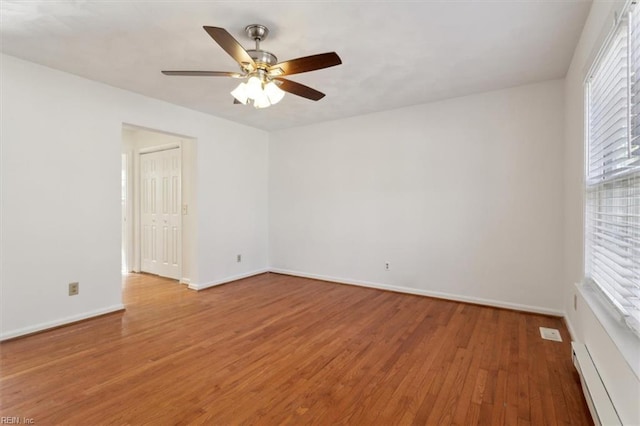 spare room with wood-type flooring, a baseboard heating unit, and ceiling fan