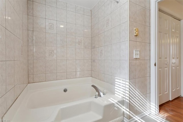 bathroom with tile walls, hardwood / wood-style floors, and a bathtub