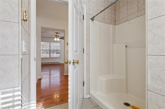 bathroom with tile patterned flooring, ceiling fan, a shower, and baseboard heating