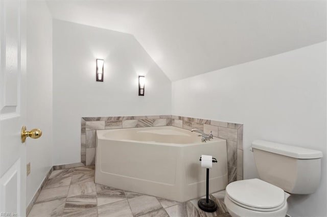 bathroom featuring a tub to relax in, lofted ceiling, and toilet