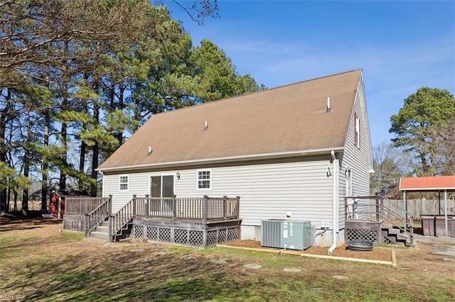 rear view of house with central AC unit, a yard, and a deck